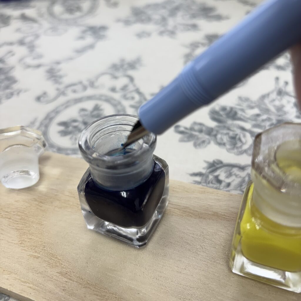 万年筆を薬瓶に入れたインクに浸している様子
