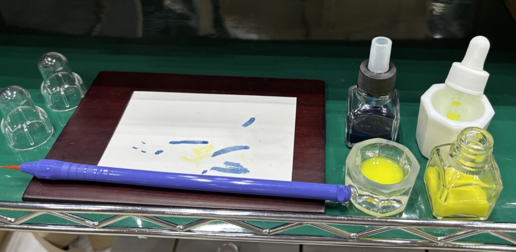 ハケ薬瓶に入れたインクを紙に塗っている様子|塗布用に便利な小さなガラス容器