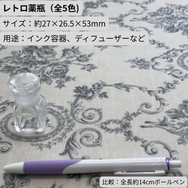 レトロ薬瓶（全5色・高さ約50mm）。クリアを撮影、比較用に全長14cmボールペンを配置。